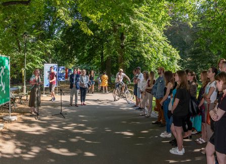 fotografia. wystawa Wyszehrad to ludzie na krakowskich plantach. dyrektor instytutu kultury willa decjusza dominika kasprowicz przemawia, otwierając wystawę. dookoła tłum ludzi.